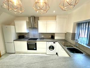 a kitchen with white cabinets and a washing machine at Antrim Hideaway in Liverpool