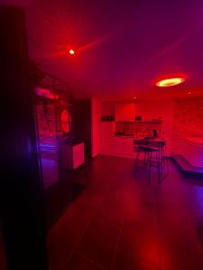 een keuken met rode verlichting en een tafel in een kamer bij Msroom in Le Val-dʼAjol