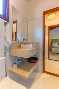 y baño con lavabo y espejo. en Kalug - 6 suítes casal, Sauna, Piscina privativa e Área gourmet completa no Centro de Trancoso!, en Trancoso