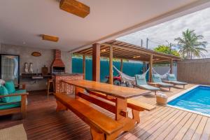 una terraza con mesa y sillas y una piscina en Kalug - 6 suítes casal, Sauna, Piscina privativa e Área gourmet completa no Centro de Trancoso!, en Trancoso