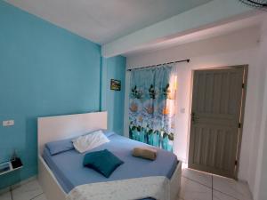 een slaapkamer met een bed met blauwe muren en een deur bij Guest House Palmeiras in Cabo Frio
