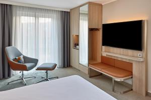 ein Hotelzimmer mit einem Bett, einem TV und einem Stuhl in der Unterkunft Courtyard by Marriott Schwerin in Schwerin