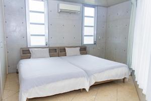 1 Schlafzimmer mit einem großen weißen Bett und 2 Fenstern in der Unterkunft Shiraho Villa - Vacation STAY 20487v in Shiraho