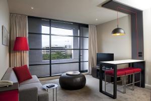 a living room with a couch and a table and a window at Mantra Hindmarsh Square in Adelaide