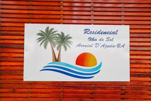 un cartello su un muro con una palma in acqua di Residencial Ilha do Sol a Arraial d'Ajuda