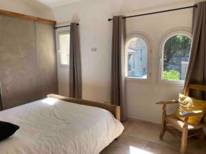 een slaapkamer met een bed en een stoel en 2 ramen bij Domaine Dupaïs, 15 min du centre d’Aix en Provence in Aix-en-Provence