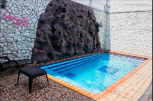 a swimming pool with a rock wall and a table and a stool at Apartahotel Romor in Cali