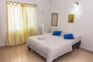 a bedroom with a bed with blue pillows and a window at Apartahotel Romor in Cali