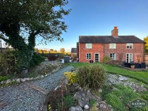 an old brick house with a garden in front of it at Luxury cottage, 13 guests with 2 hot tubs in Hoar Cross, Staffs in Newborough