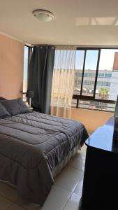 a bedroom with a bed and a large window at Ideal familias, frente a la playa. Excelente ubicación in Iquique