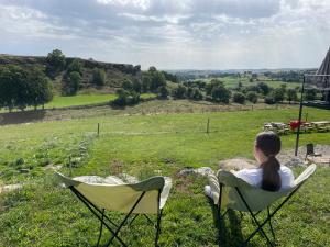 a woman sitting in a chair in a field at Le Buron du Bessou in Saint-Urcize