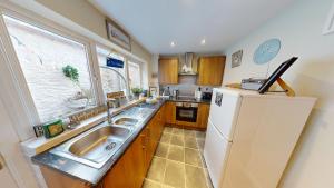 a kitchen with a sink and a refrigerator at Saltys Cottage, Brixham - 2 min walk to the harbour in Brixham