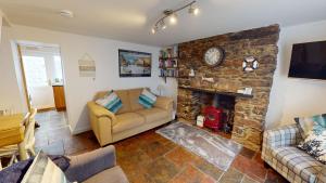 a living room with a couch and a stone fireplace at Saltys Cottage, Brixham - 2 min walk to the harbour in Brixham