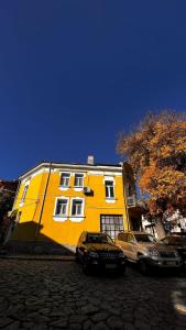 HANCHO - OLD TOWN CENTER PLOVDIV في بلوفديف: مبنى اصفر فيه سيارات تقف امامه
