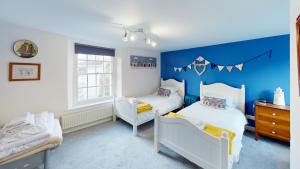 a bedroom with two beds and a blue wall at Saltys Cottage, Brixham - 2 min walk to the harbour in Brixham