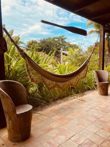 a hammock on a patio with two chairs and trees at Pousada Terra Caraiva in Caraíva