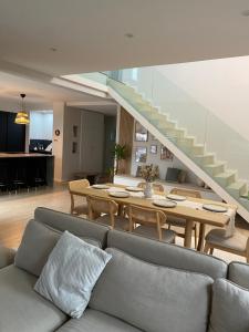 a living room with a couch and a table and stairs at Maison spacieuse au calme proche Colmar avec piscine in Niederentzen