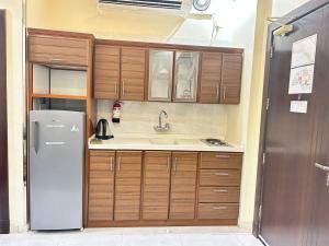 a kitchen with wooden cabinets and a refrigerator at شقق ريجنسي للشقق المخدومة in Jazan