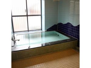 y baño con bañera y ventana. en Tsukuba Town Hotel - Vacation STAY 65188v en Joso