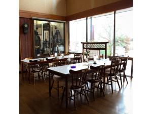 ein Esszimmer mit Tischen, Stühlen und Fenstern in der Unterkunft Tsukuba Town Hotel - Vacation STAY 65211v in Joso