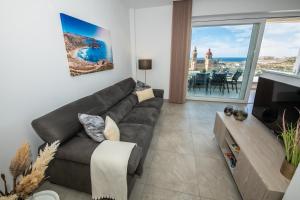 sala de estar con sofá y TV en Clifftop Modern Apartment, en Mellieħa