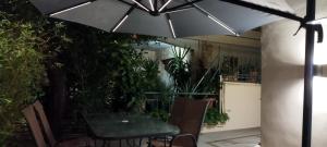 einen Tisch und Stühle unter einem Sonnenschirm auf einer Terrasse in der Unterkunft Μία γκαρσονιέρα με γούστο για επισκέπτες με άποψη in Athen