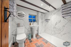 ein Bad mit einem WC, einem Waschbecken und einer Dusche in der Unterkunft Luxury cottage, 13 guests with 2 hot tubs in Hoar Cross, Staffs in Newborough