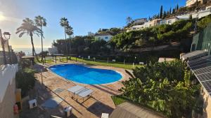 uma vista para uma piscina com palmeiras e casas em Villa la Colina with heated pool and jacuzzi em Salobreña