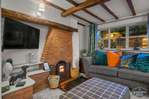 sala de estar con sofá y chimenea en Luxury cottage, 13 guests with 2 hot tubs in Hoar Cross, Staffs, en Newborough