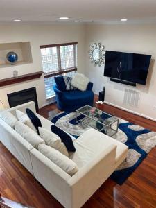 a living room with a white couch and a tv at Beautiful & Luxurious 2 bed 2 & half bth & 2 car attached garage TownHouse in Falls Church in Falls Church