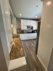a large kitchen with white cabinets and wooden floors at Beautiful & Luxurious 2 bed 2 & half bth & 2 car attached garage TownHouse in Falls Church in Falls Church