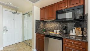 a kitchen with wooden cabinets and a microwave at La Mer Beachfront Resort in Cape May