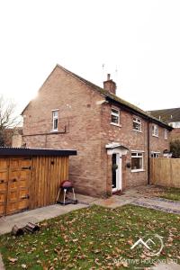 a brick house with a garage and a fence at Lilly Cottage Romantic Log Burner and Sauna Retreat in Chester