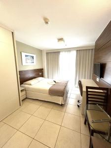 um quarto com uma cama, uma secretária e uma cadeira em F1104 Flat de ótima localização e fácil acesso em Brasília