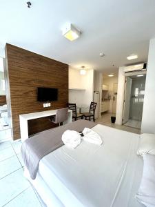 um quarto com uma cama branca e uma televisão na parede em F1104 Flat de ótima localização e fácil acesso em Brasília