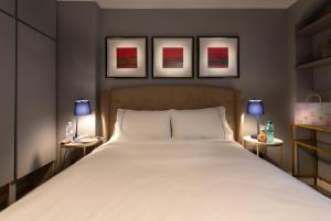 a bedroom with a large bed with three pictures on the wall at THE PAD at Sloane Square in London