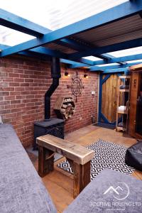 a patio with a wooden bench and a brick wall at Lilly Cottage Romantic Log Burner and Sauna Retreat in Chester