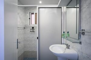 een witte badkamer met een wastafel en een douche bij Ocean Breeze in Porto Moniz