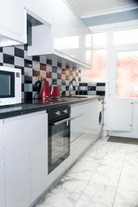 曼徹斯特的住宿－CHEADLE HOUSE HOLIDAYS，白色的厨房配有炉灶和微波炉。