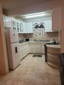 uma cozinha com armários brancos e um frigorífico branco em StayHaven Escapes em Saint Michael