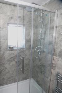 a shower with a glass door in a bathroom at CHEADLE HOUSE HOLIDAYS in Manchester
