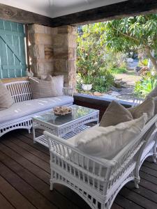 un porche con sillas blancas y una mesa en Avalon Beach Cottage- The Islander, en Avalon