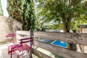 a red chair sitting on a fence next to a pool at Appartement 50m2 parfait état avec piscine privée in Bordeaux