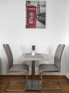 a table with two chairs and a red phone booth at Allurian Apartment - City kvart in Podgorica