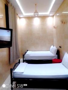 a room with two beds and a flat screen tv at R&eacute;sidence Miramare Marrakech in Marrakech