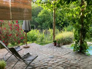 a patio with a chair and a umbrella and some flowers at Las Pircas, casa de campo in Ciudad Lujan de Cuyo