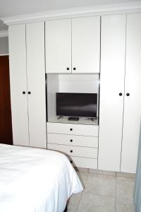 um quarto branco com uma televisão e uma cama em Soldout Camp 2 em Pretoria
