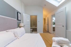 a white bedroom with a bed and a bathroom at Unique 3 Beds 2 Baths Abbey Rd St John's Wood in London