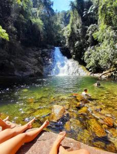 people laying on a rock in a river with a waterfall at Alegria casa 3 dorms Cond Fechado churrasqueira piscina in Boicucanga