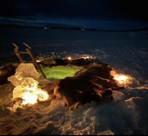 a person sitting on the ground in the snow at night at Northern Light Camp in Kiruna